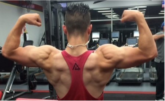 Image of Connor viewed from behind, wearing exercise gear. Weight lifting equipment in the background